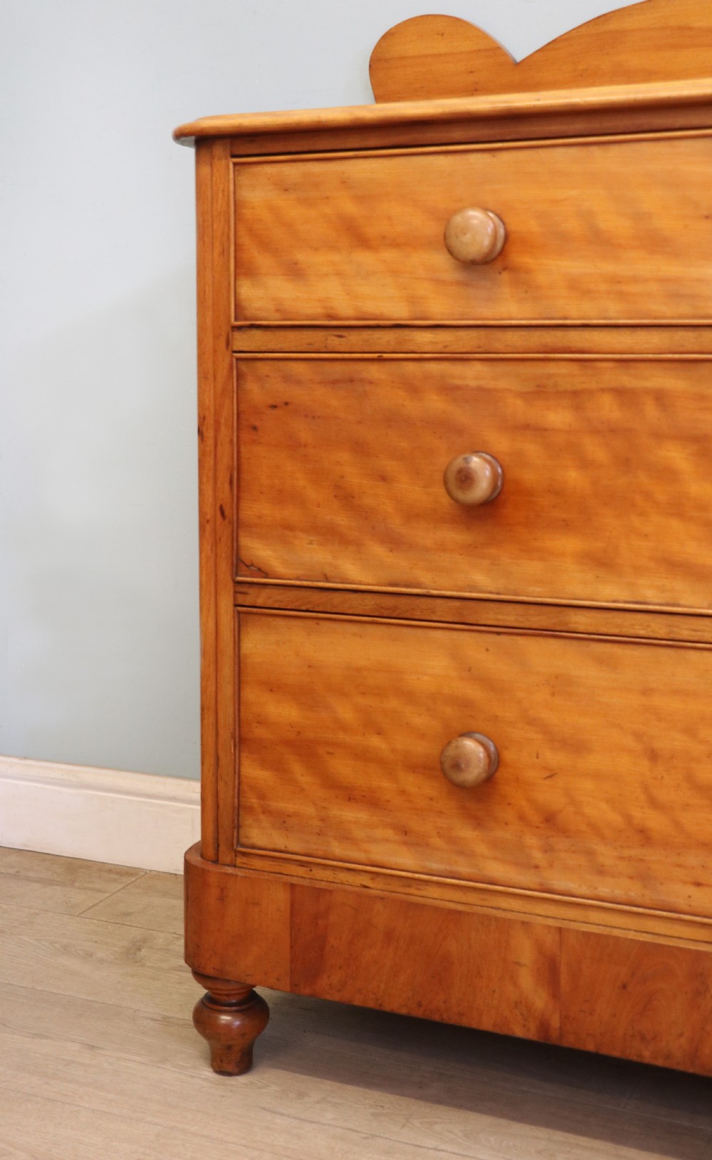 A Victorian satin birch chest of drawers featuring a shaped gallery backboard, two short over two long drawers with turned knobs, resting on a plinth base. View XIV