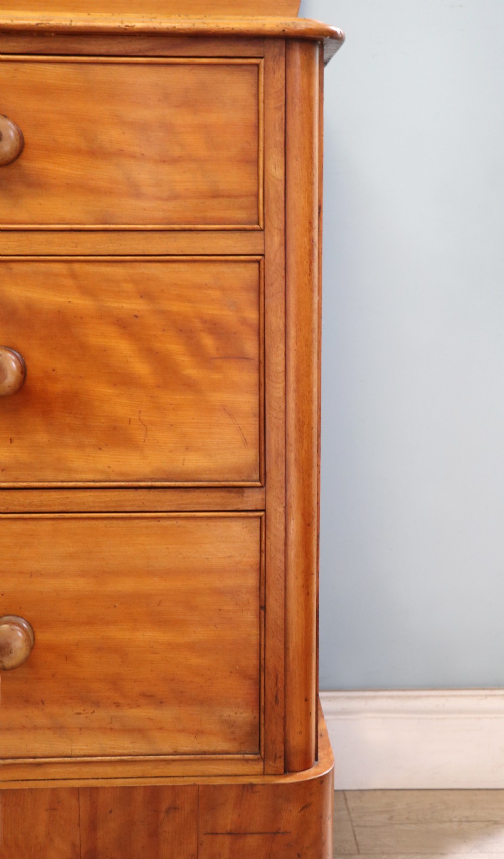 A Victorian satin birch chest of drawers featuring a shaped gallery backboard, two short over two long drawers with turned knobs, resting on a plinth base. View XV