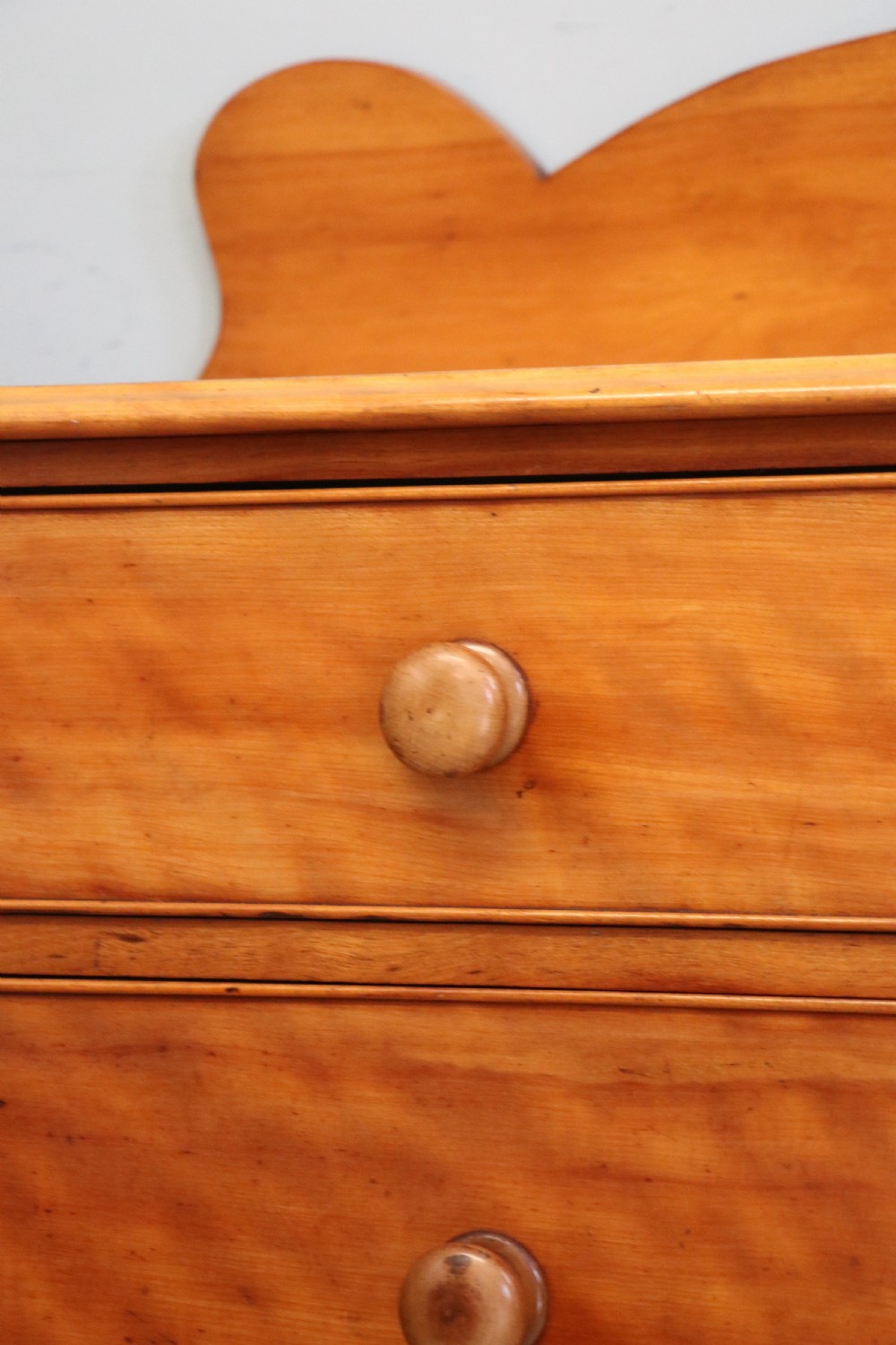 A Victorian satin birch chest of drawers featuring a shaped gallery backboard, two short over two long drawers with turned knobs, resting on a plinth base. View XVII