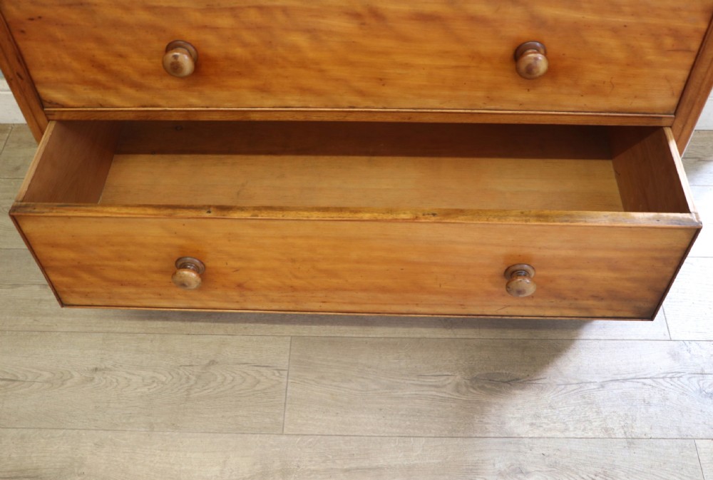 A Victorian satin birch chest of drawers featuring a shaped gallery backboard, two short over two long drawers with turned knobs, resting on a plinth base. View XXII