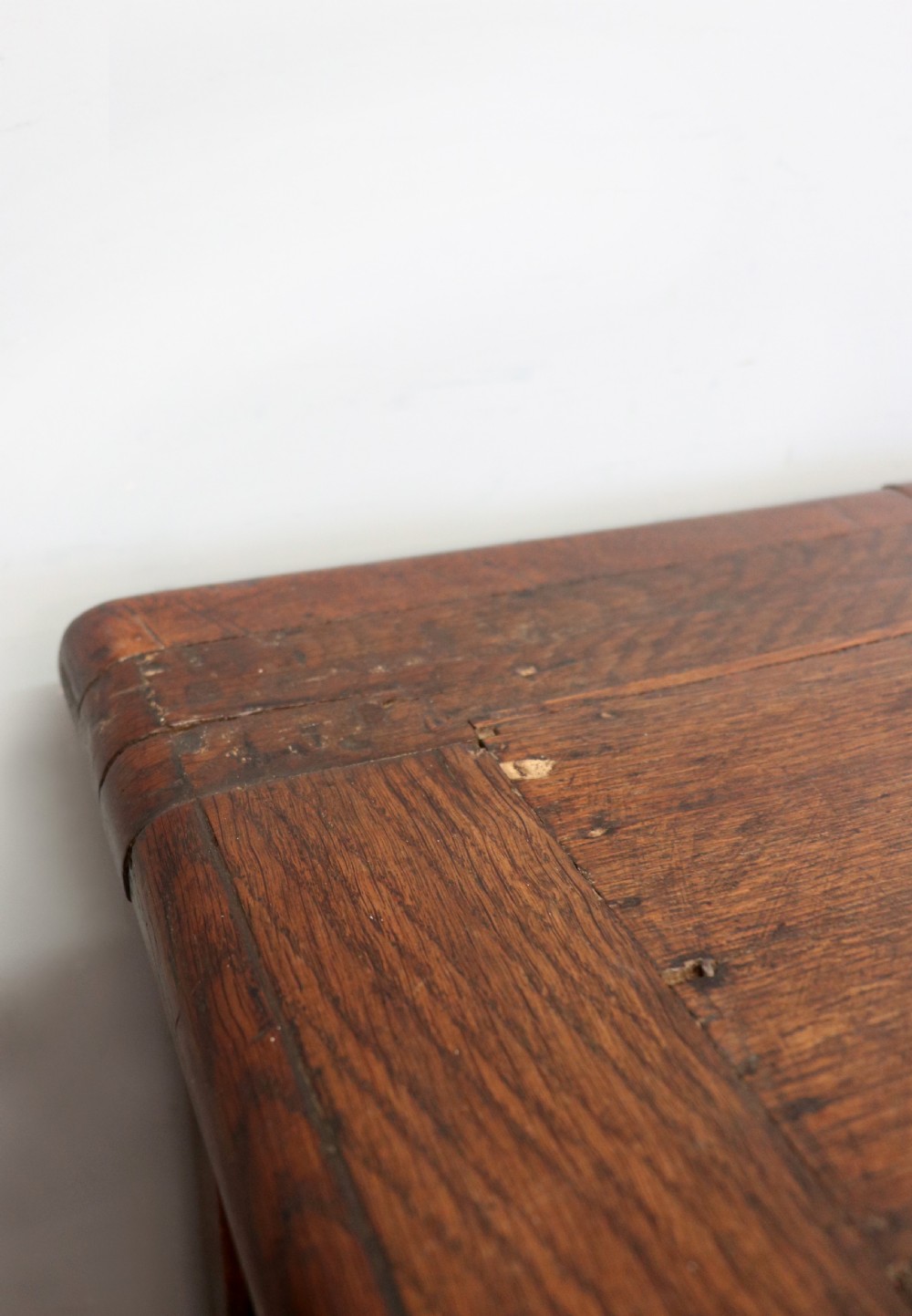 An 18th-century dark oak coffer with a hinged top lid, a carved upper frieze, and panelled lower drawers featuring brass drop handles. View VIII