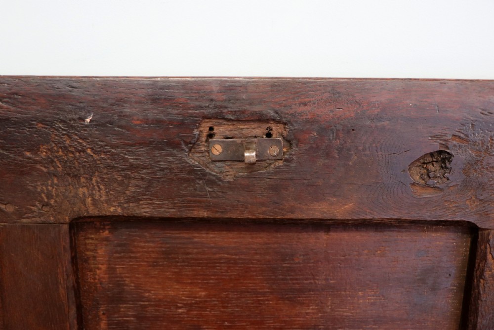 An 18th-century dark oak coffer with a hinged top lid, a carved upper frieze, and panelled lower drawers featuring brass drop handles. View XIII