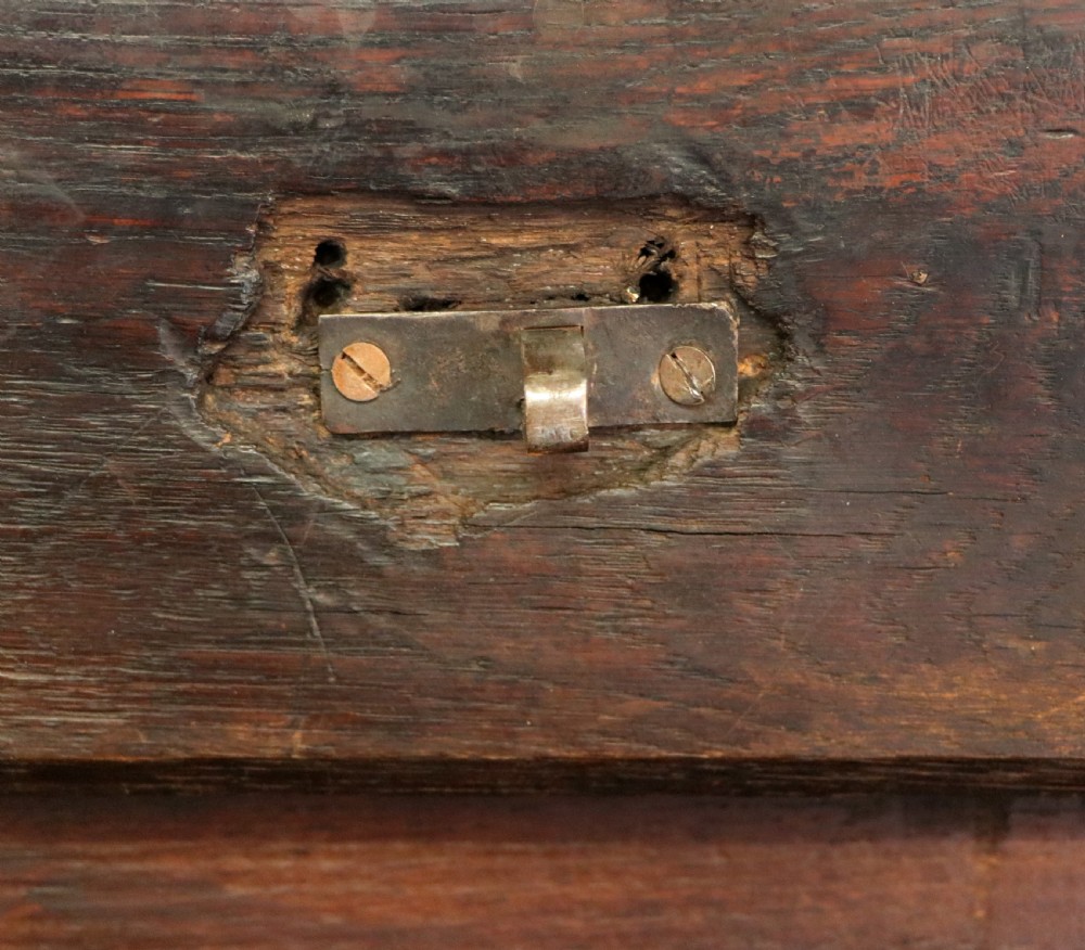 An 18th-century dark oak coffer with a hinged top lid, a carved upper frieze, and panelled lower drawers featuring brass drop handles. View XIV