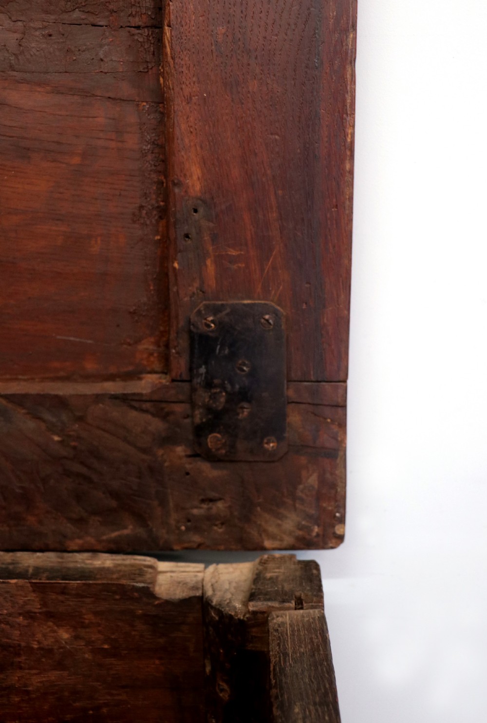An 18th-century dark oak coffer with a hinged top lid, a carved upper frieze, and panelled lower drawers featuring brass drop handles. View XVII