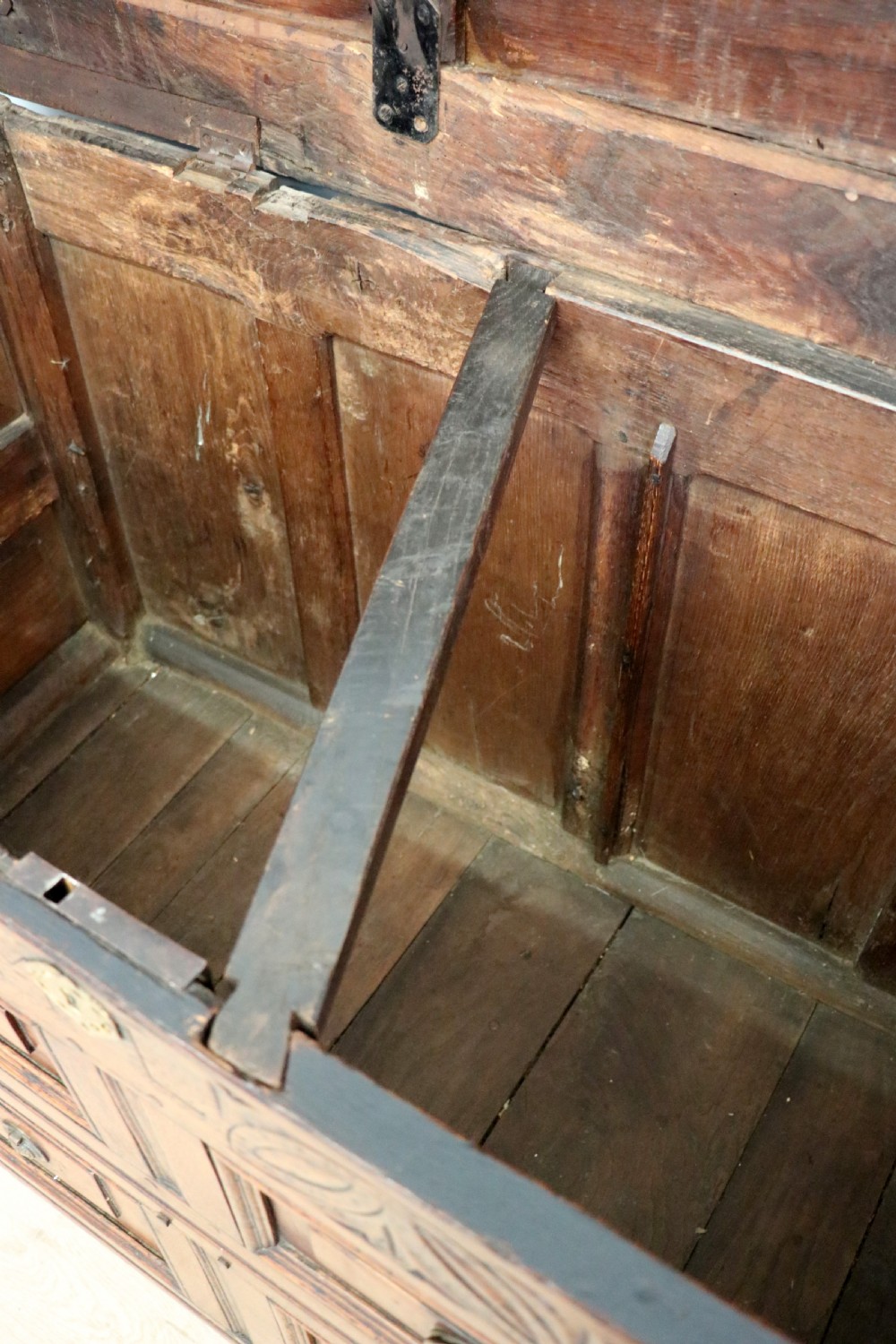 An 18th-century dark oak coffer with a hinged top lid, a carved upper frieze, and panelled lower drawers featuring brass drop handles. View XIX