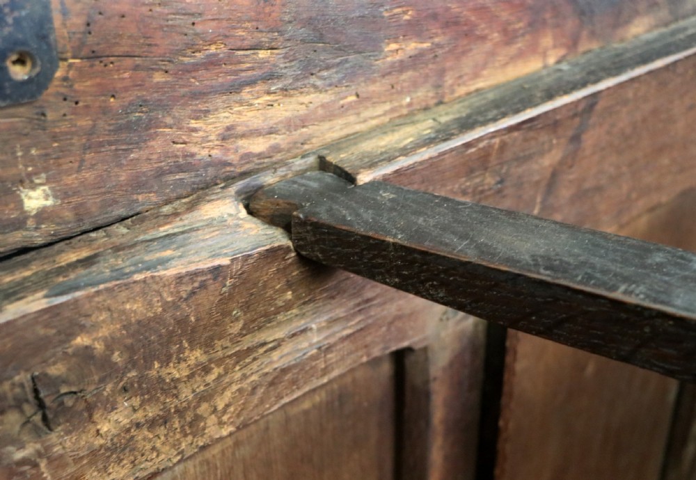 An 18th-century dark oak coffer with a hinged top lid, a carved upper frieze, and panelled lower drawers featuring brass drop handles. View XXII