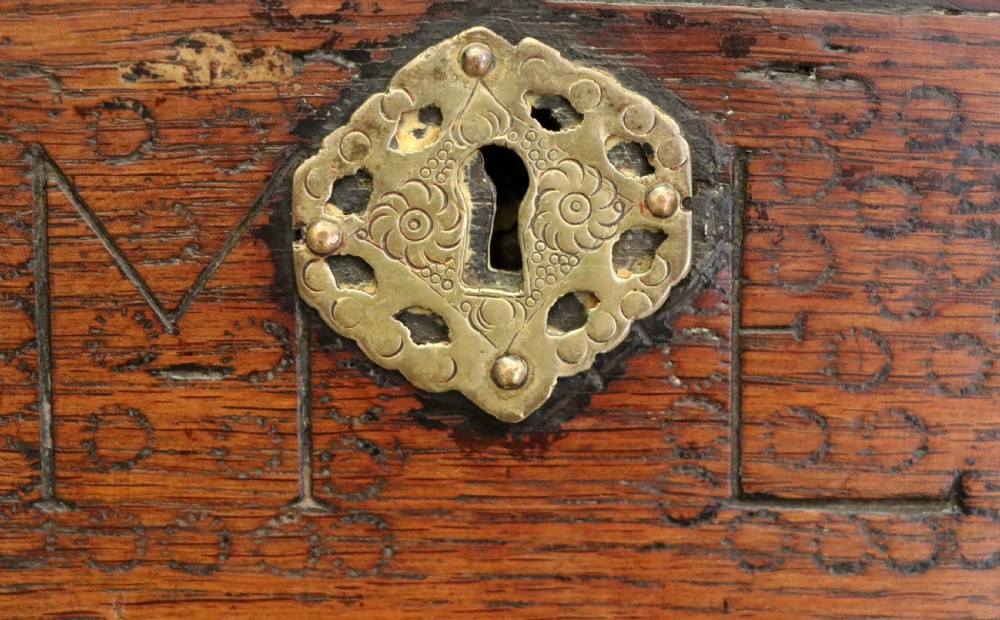 An 18th-century dark oak coffer with a hinged top lid, a carved upper frieze, and panelled lower drawers featuring brass drop handles. View XXVII