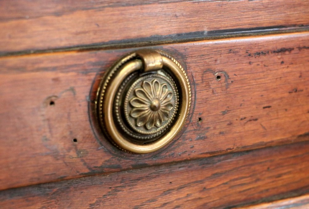 An 18th-century dark oak coffer with a hinged top lid, a carved upper frieze, and panelled lower drawers featuring brass drop handles. View XXIX
