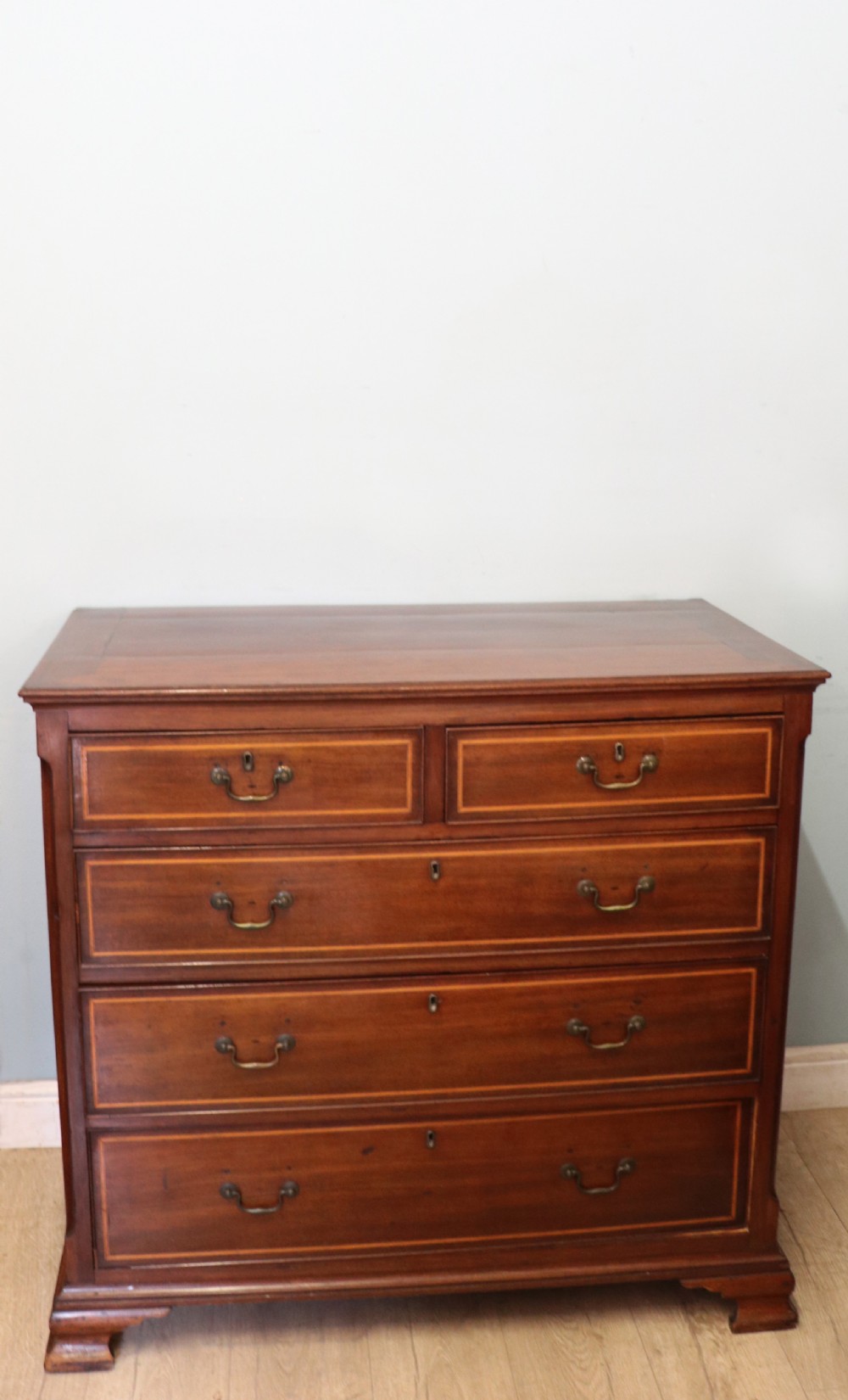 A Georgian Revival mahogany chest of drawers featuring two short drawers over three long drawers with decorative inlay and brass handles. View III