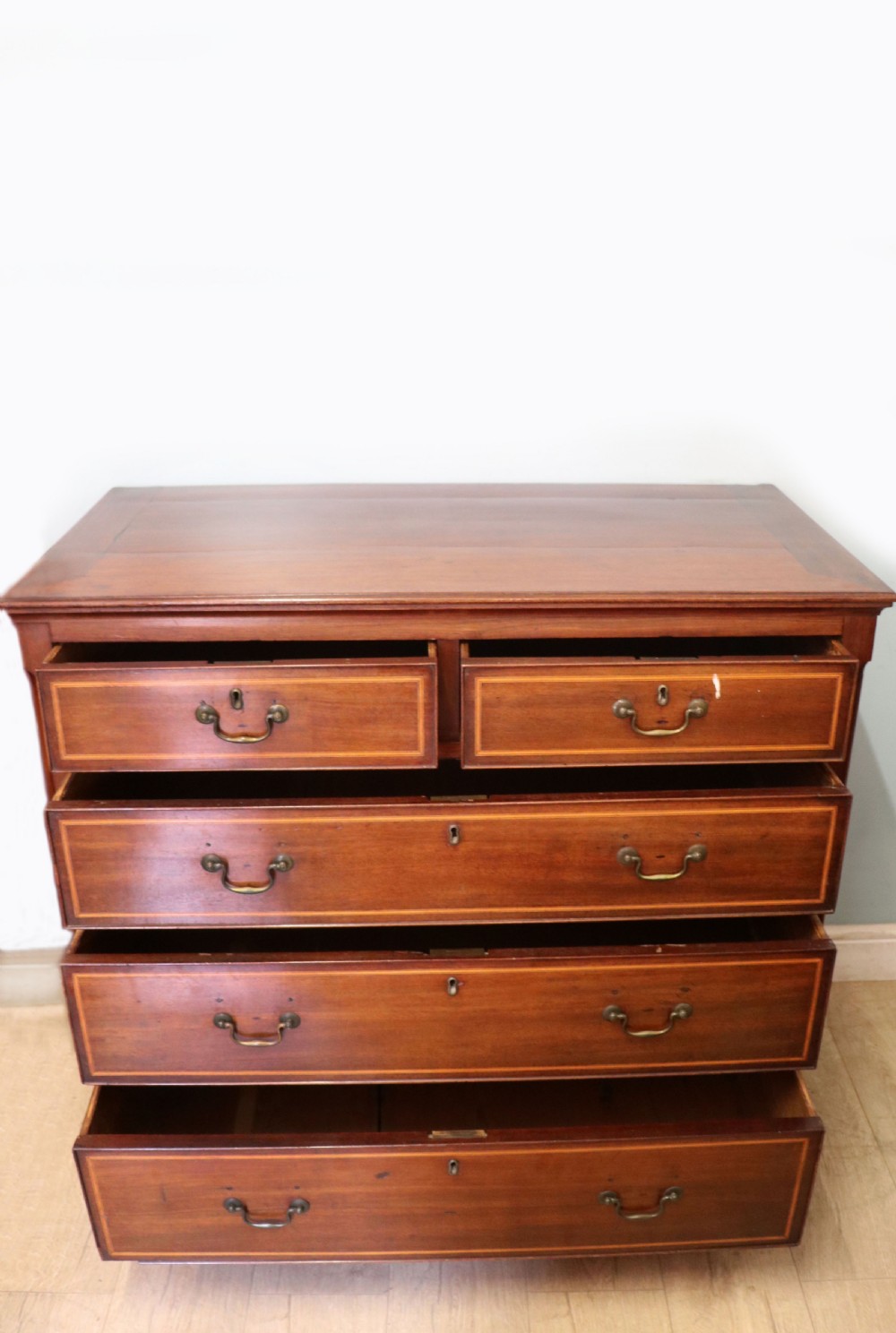 A Georgian Revival mahogany chest of drawers featuring two short drawers over three long drawers with decorative inlay and brass handles. View II