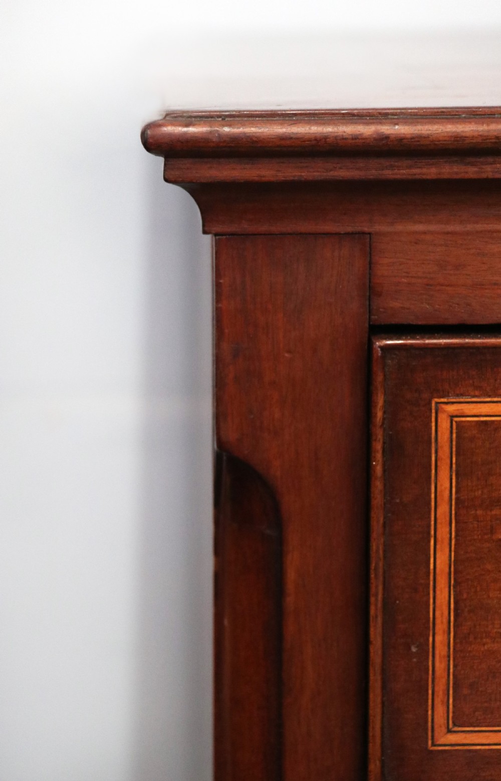 A Georgian Revival mahogany chest of drawers featuring two short drawers over three long drawers with decorative inlay and brass handles. View VI