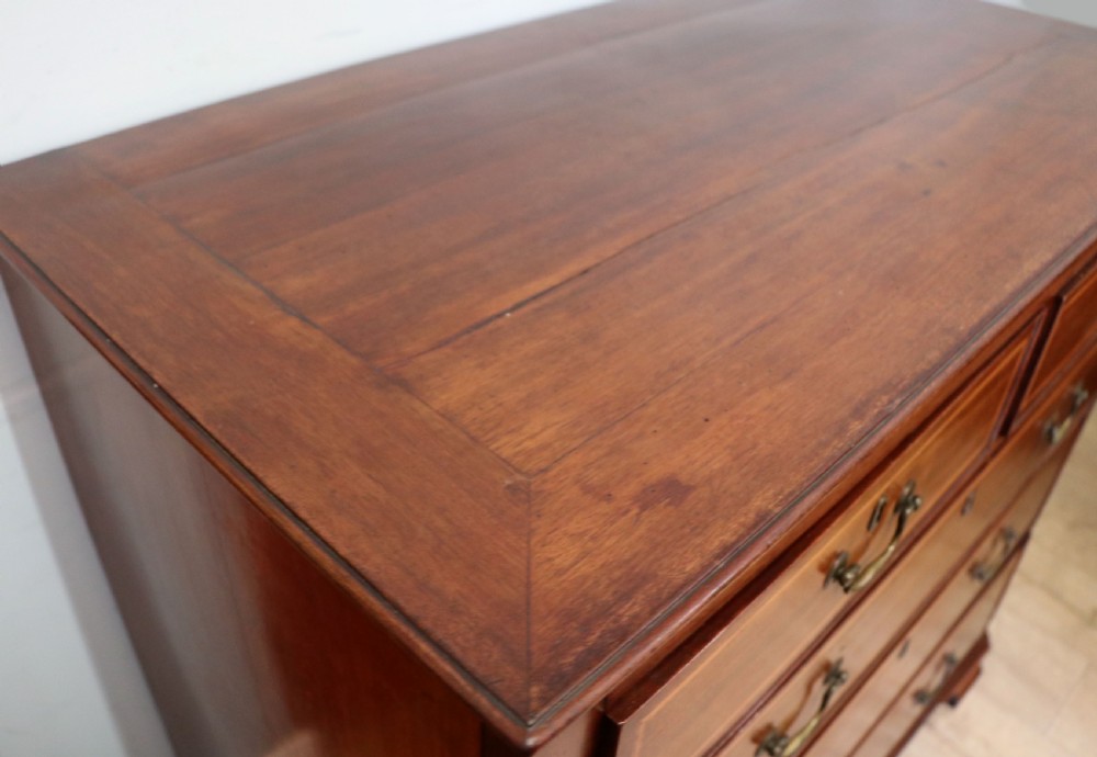 A Georgian Revival mahogany chest of drawers featuring two short drawers over three long drawers with decorative inlay and brass handles. View VII