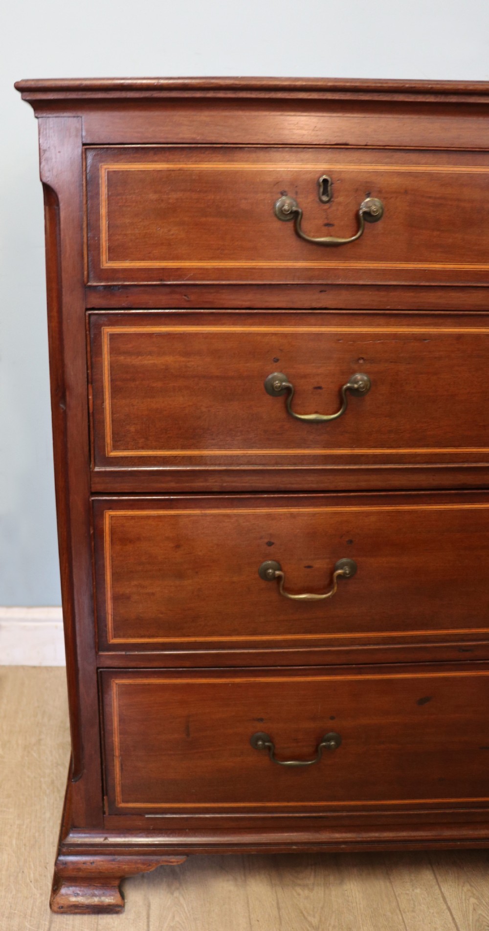 A Georgian Revival mahogany chest of drawers featuring two short drawers over three long drawers with decorative inlay and brass handles. View XI