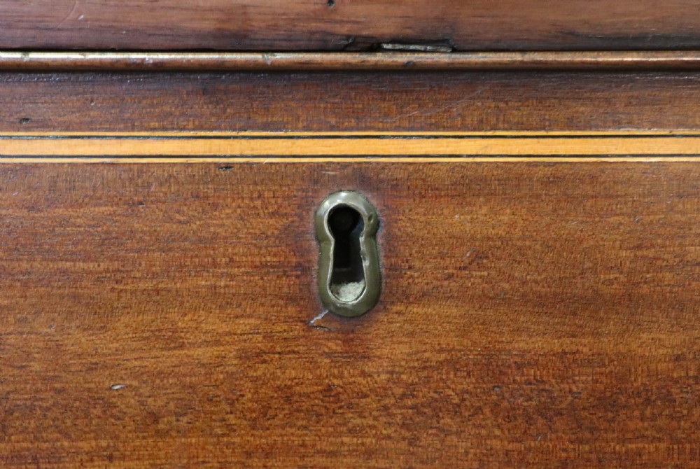 A Georgian Revival mahogany chest of drawers featuring two short drawers over three long drawers with decorative inlay and brass handles. View XII