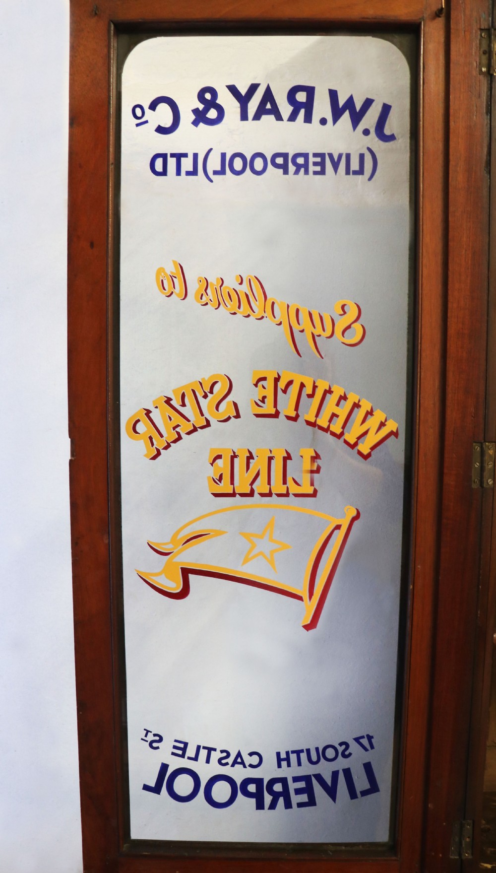 A late Victorian mahogany two-piece bookcase cabinet featuring upper glazed doors with gilded advertising lettering above two frieze drawers and a cupboard base. View XII