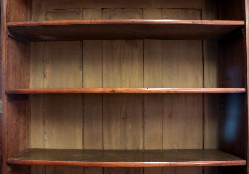 A late Victorian mahogany two-piece bookcase cabinet featuring upper glazed doors with gilded advertising lettering above two frieze drawers and a cupboard base. View XV