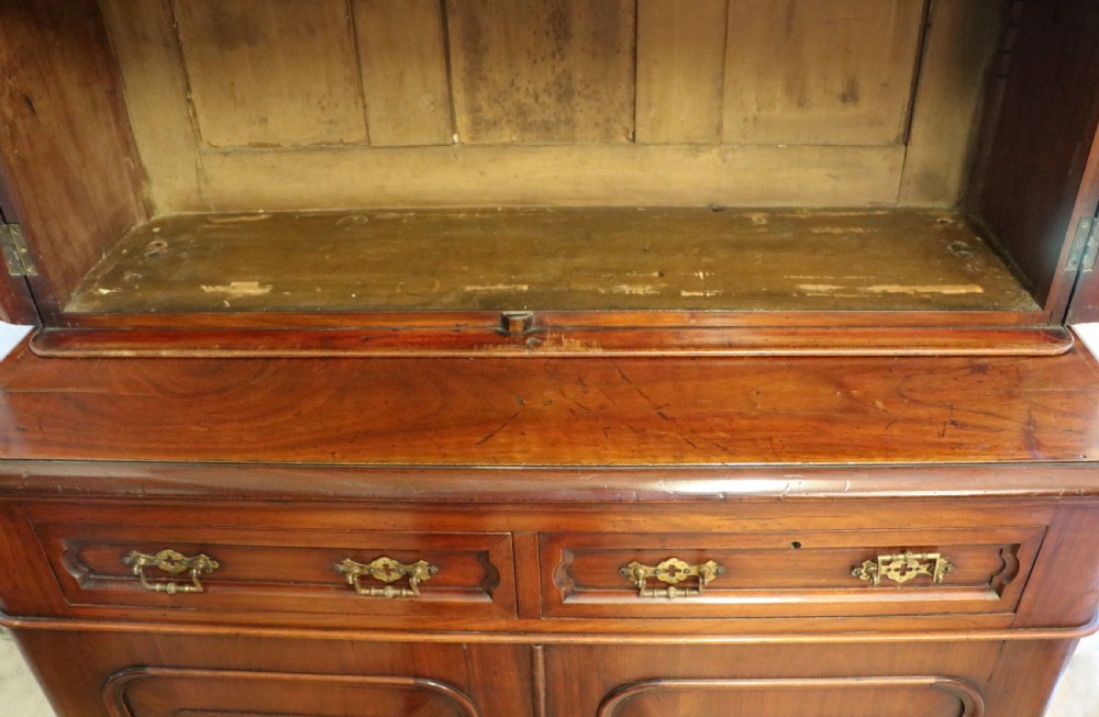 A late Victorian mahogany two-piece bookcase cabinet featuring upper glazed doors with gilded advertising lettering above two frieze drawers and a cupboard base. View XIX