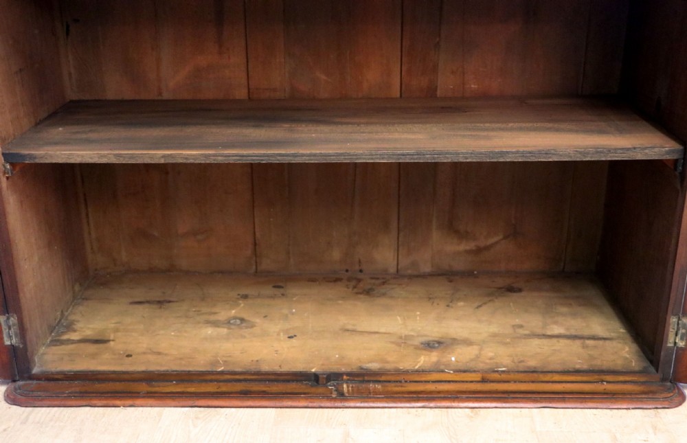 A late Victorian mahogany two-piece bookcase cabinet featuring upper glazed doors with gilded advertising lettering above two frieze drawers and a cupboard base. View XXII