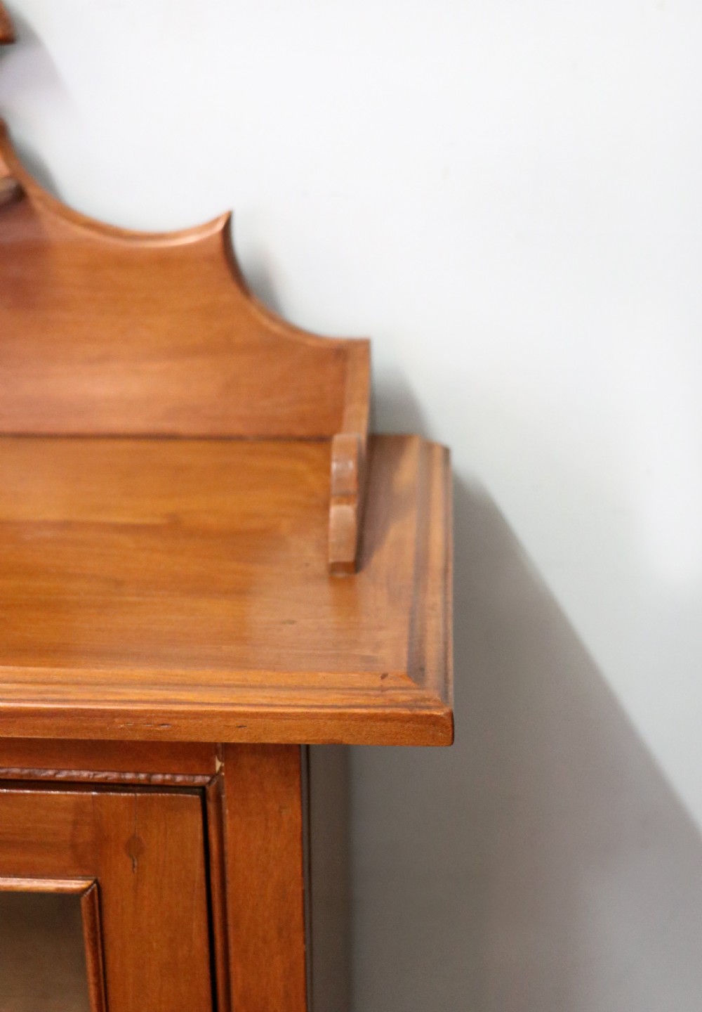 A Victorian American walnut glazed display cabinet featuring a shaped top pediment and hand-painted Frys Chocolate advertising on the single glass door. View XI