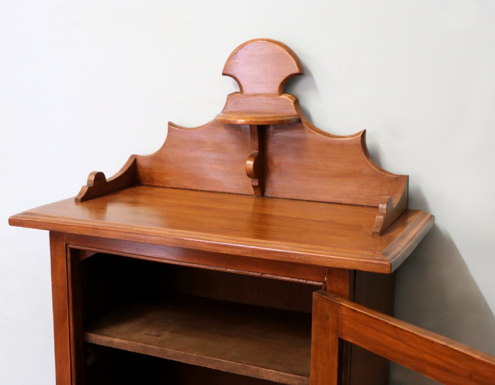 A Victorian American walnut glazed display cabinet featuring a shaped top pediment and hand-painted Frys Chocolate advertising on the single glass door. View XII