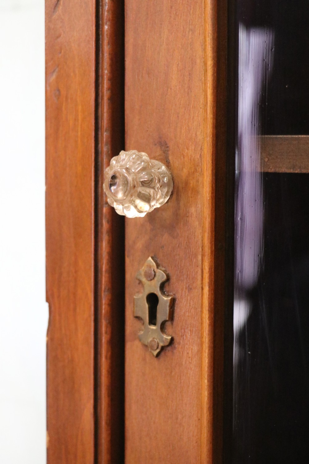 A Victorian American walnut glazed display cabinet featuring a shaped top pediment and hand-painted Frys Chocolate advertising on the single glass door. View XV