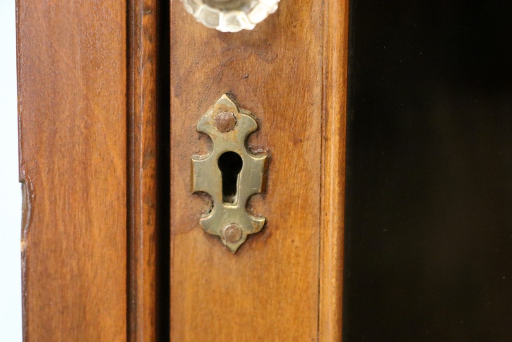 A Victorian American walnut glazed display cabinet featuring a shaped top pediment and hand-painted Frys Chocolate advertising on the single glass door. View XVI