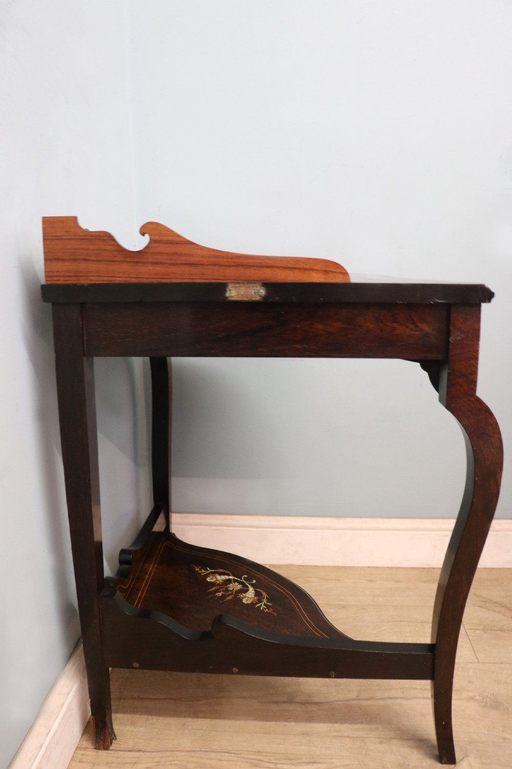 An early twentieth-century Sheraton Revival mahogany corner table featuring elaborate floral marquetry inlay, curved legs, and an undertier shelf. View V