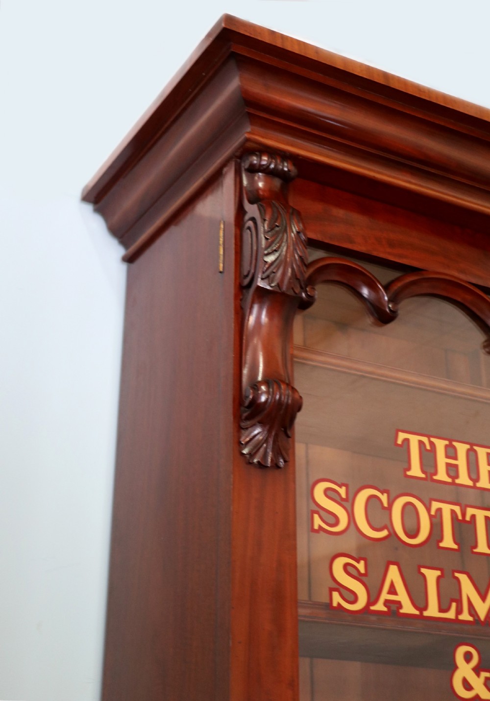 A Victorian mahogany two-height glazed bookcase featuring gilt advertising lettering on the glass doors and lower panelled doors. View X