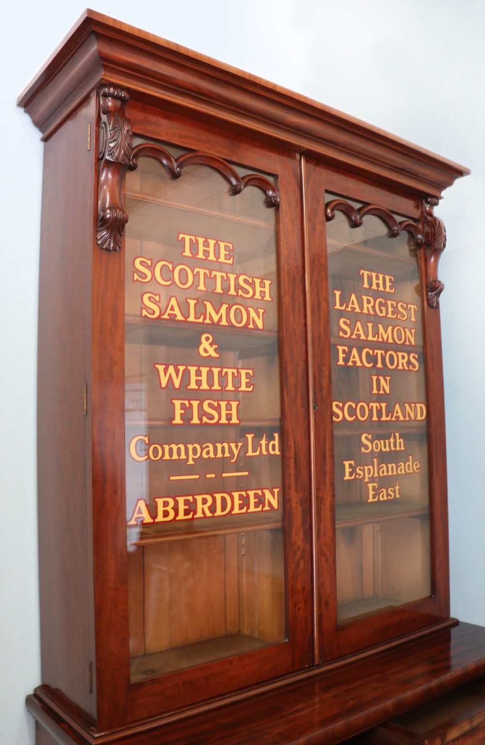 A Victorian mahogany two-height glazed bookcase featuring gilt advertising lettering on the glass doors and lower panelled doors. View XIII