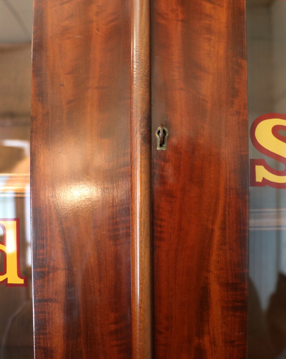 A Victorian mahogany two-height glazed bookcase featuring gilt advertising lettering on the glass doors and lower panelled doors. View XIV
