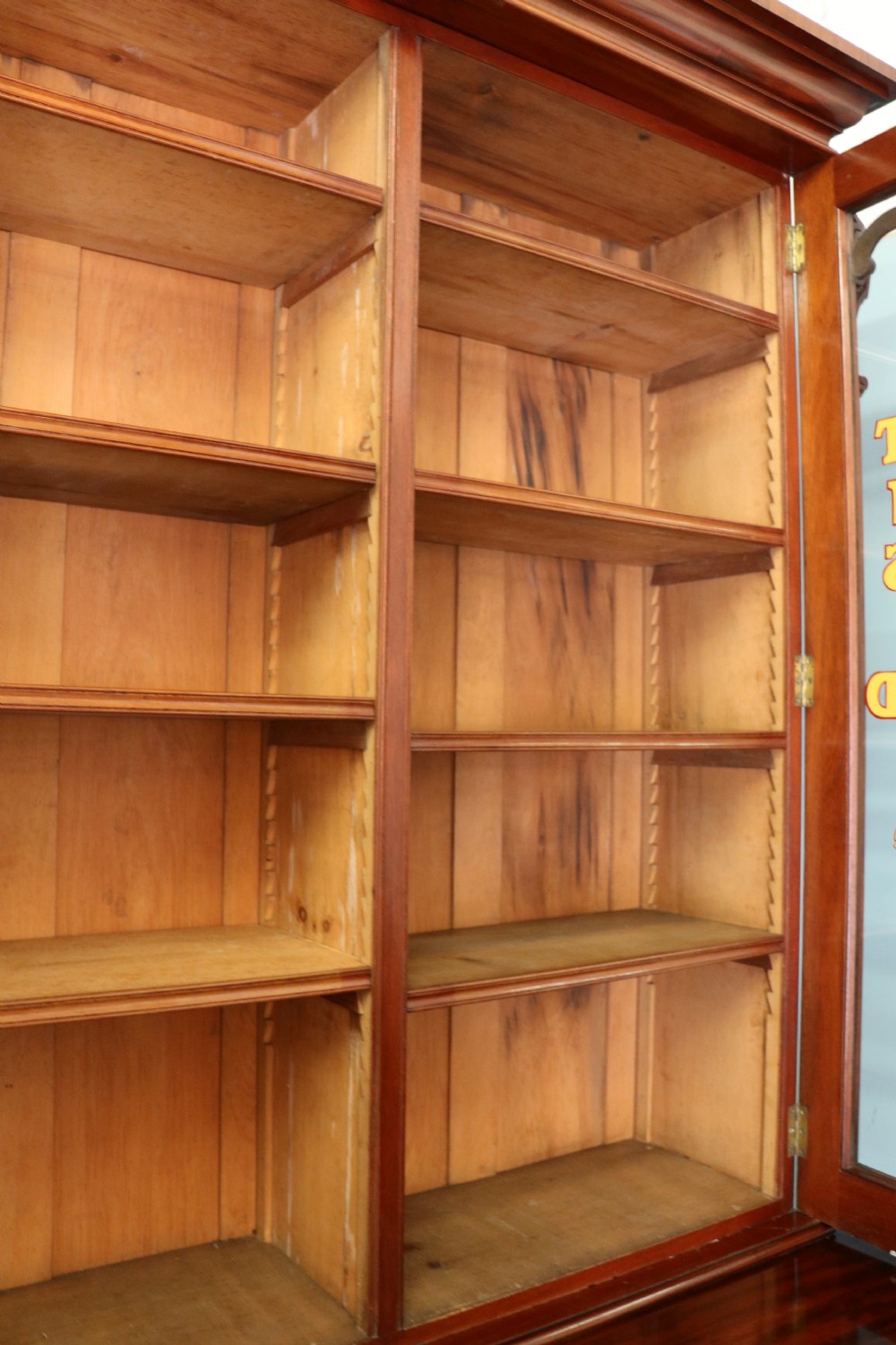 A Victorian mahogany two-height glazed bookcase featuring gilt advertising lettering on the glass doors and lower panelled doors. View XX