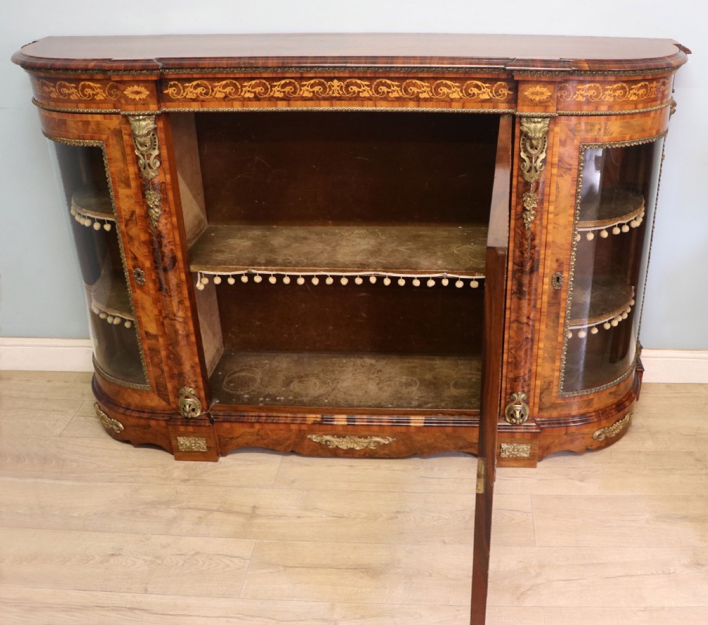 A Victorian walnut credenza featuring floral marquetry inlay, a central glazed door, two curved glass side doors, and gilt metal mounts. View II