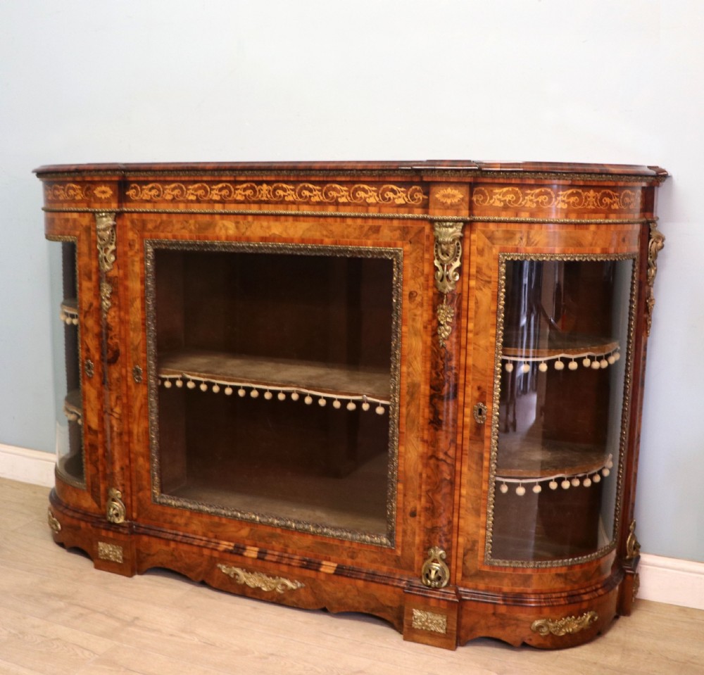 A Victorian walnut credenza featuring floral marquetry inlay, a central glazed door, two curved glass side doors, and gilt metal mounts. View VI