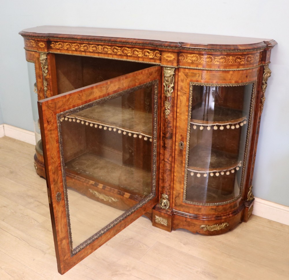 A Victorian walnut credenza featuring floral marquetry inlay, a central glazed door, two curved glass side doors, and gilt metal mounts. View VII
