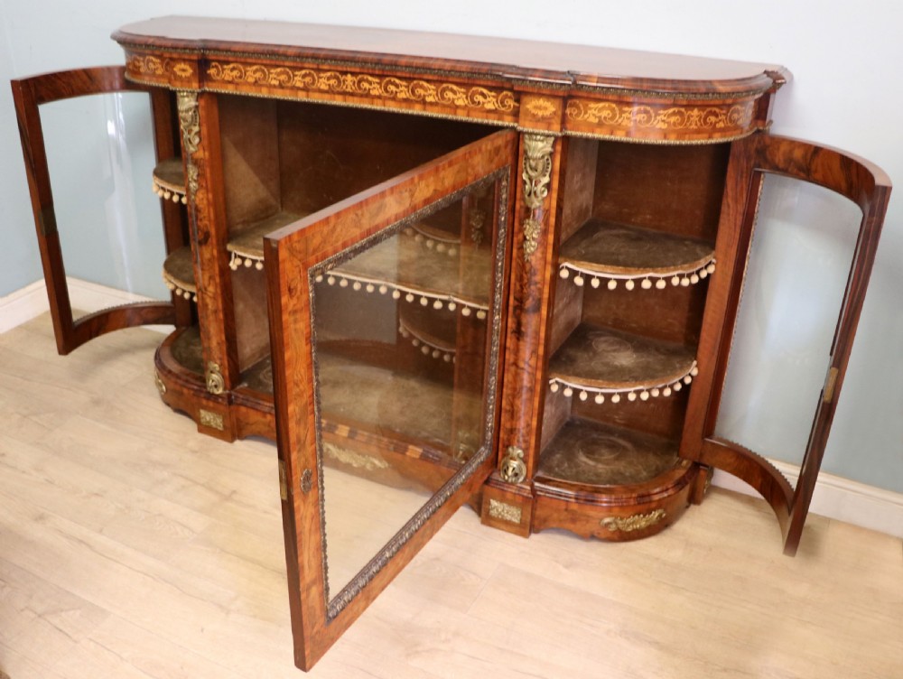 A Victorian walnut credenza featuring floral marquetry inlay, a central glazed door, two curved glass side doors, and gilt metal mounts. View VIII