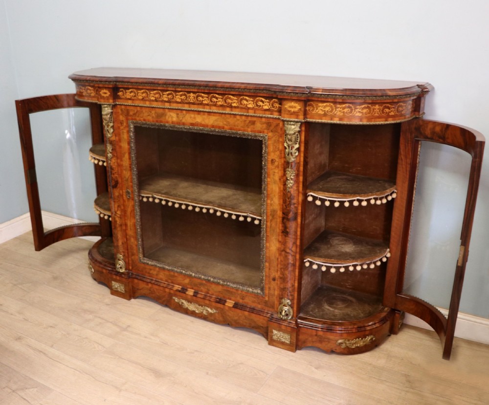 A Victorian walnut credenza featuring floral marquetry inlay, a central glazed door, two curved glass side doors, and gilt metal mounts. View IX