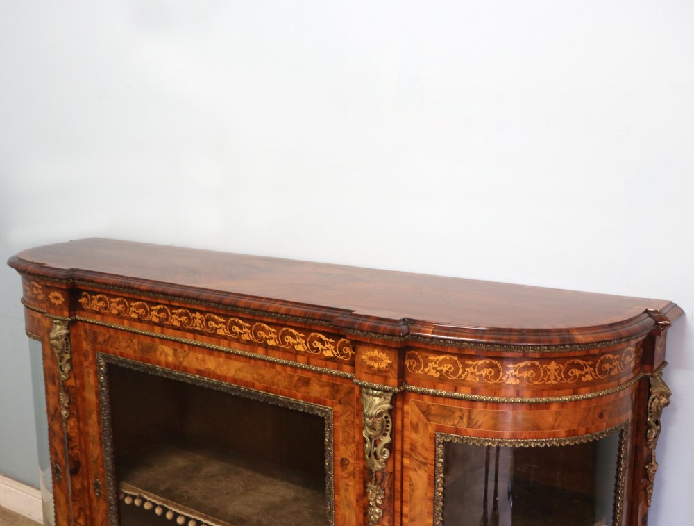 A Victorian walnut credenza featuring floral marquetry inlay, a central glazed door, two curved glass side doors, and gilt metal mounts. View XI