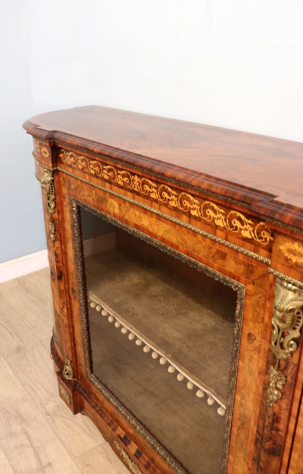 A Victorian walnut credenza featuring floral marquetry inlay, a central glazed door, two curved glass side doors, and gilt metal mounts. View XII
