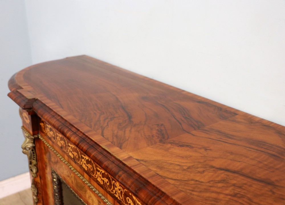 A Victorian walnut credenza featuring floral marquetry inlay, a central glazed door, two curved glass side doors, and gilt metal mounts. View XIII