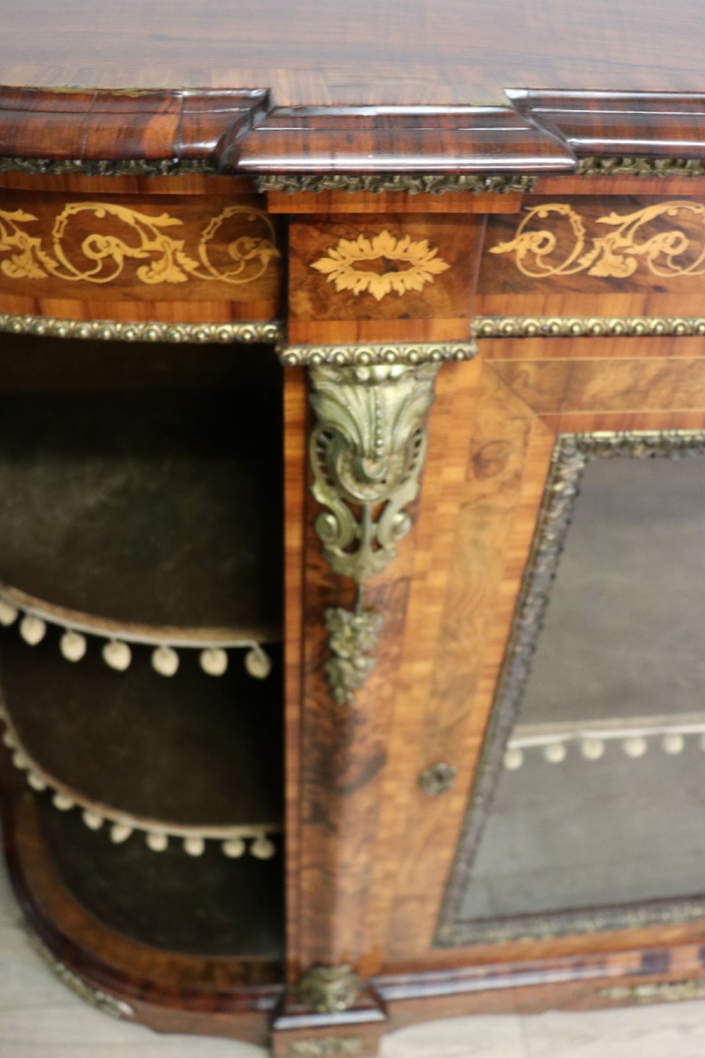 A Victorian walnut credenza featuring floral marquetry inlay, a central glazed door, two curved glass side doors, and gilt metal mounts. View XIX