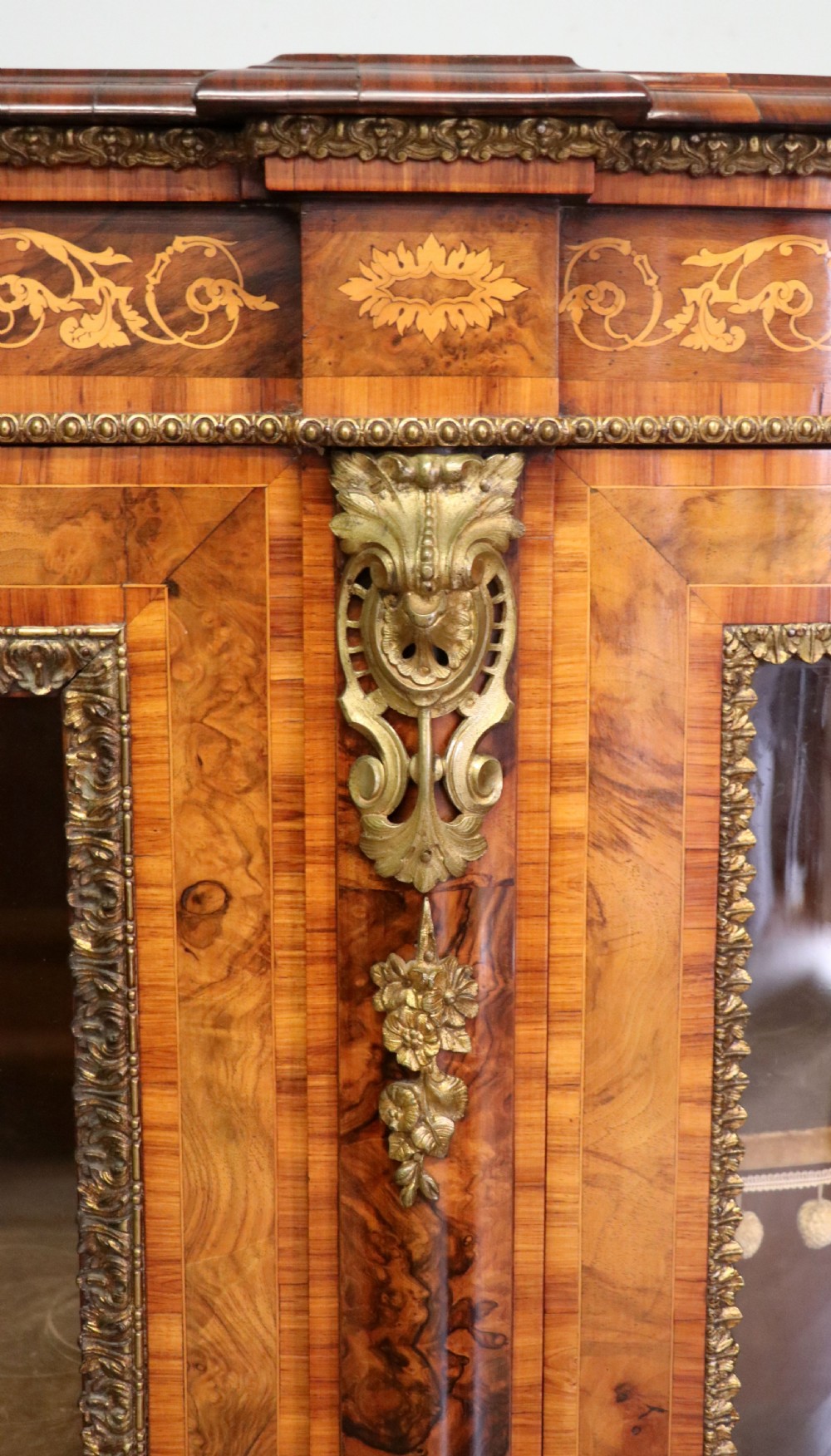 A Victorian walnut credenza featuring floral marquetry inlay, a central glazed door, two curved glass side doors, and gilt metal mounts. View XXI