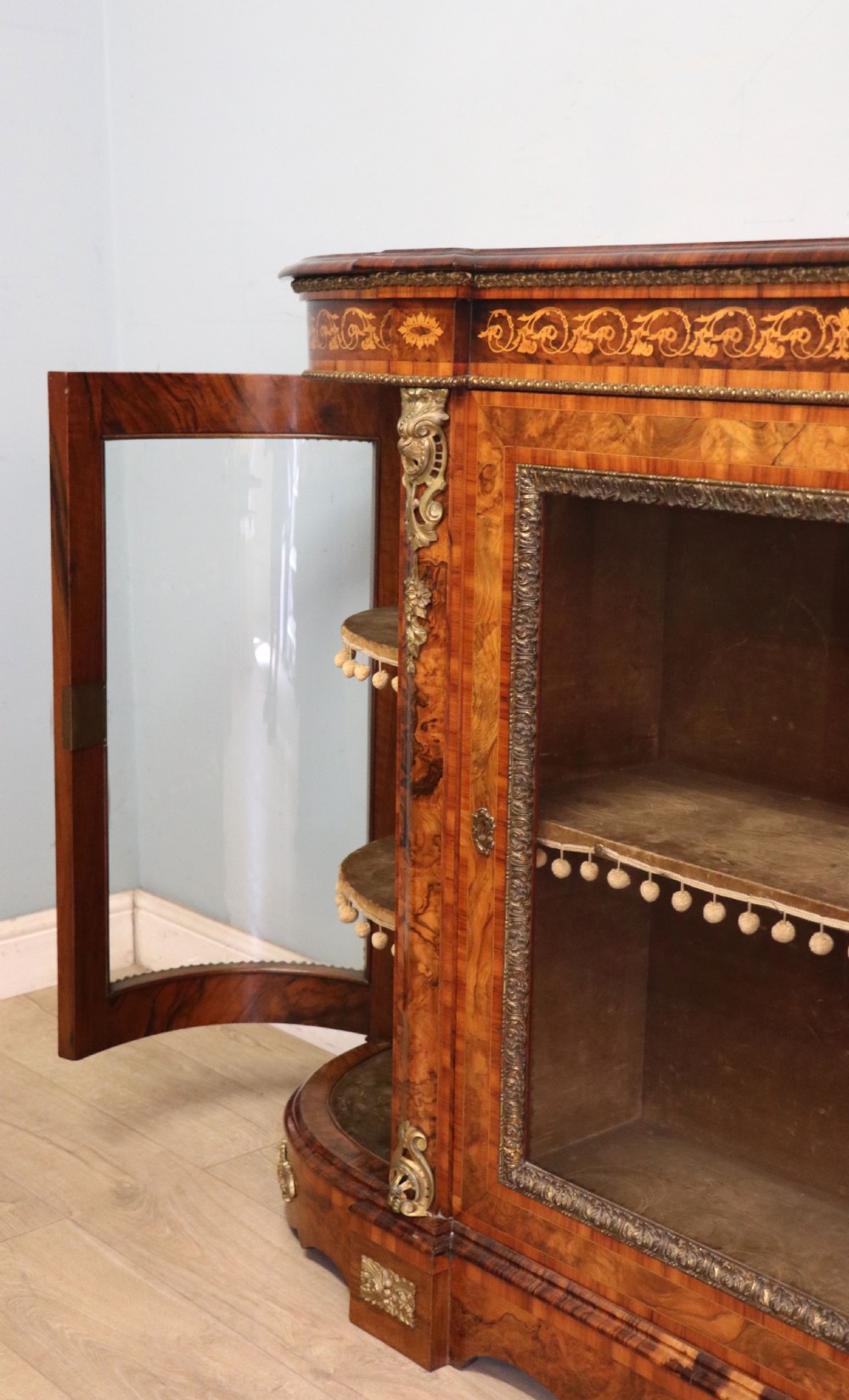 A Victorian walnut credenza featuring floral marquetry inlay, a central glazed door, two curved glass side doors, and gilt metal mounts. View XXII