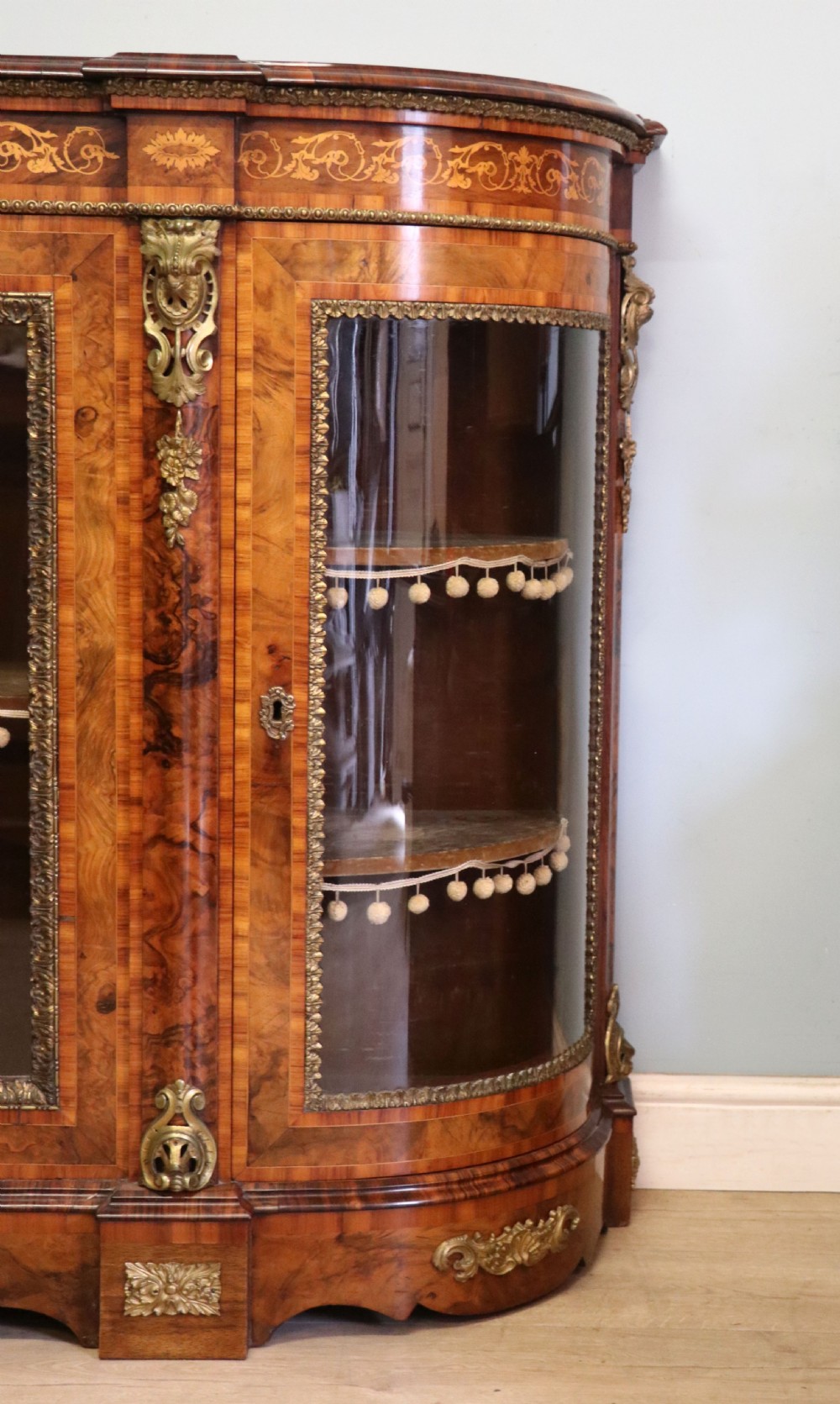 A Victorian walnut credenza featuring floral marquetry inlay, a central glazed door, two curved glass side doors, and gilt metal mounts. View XXIII