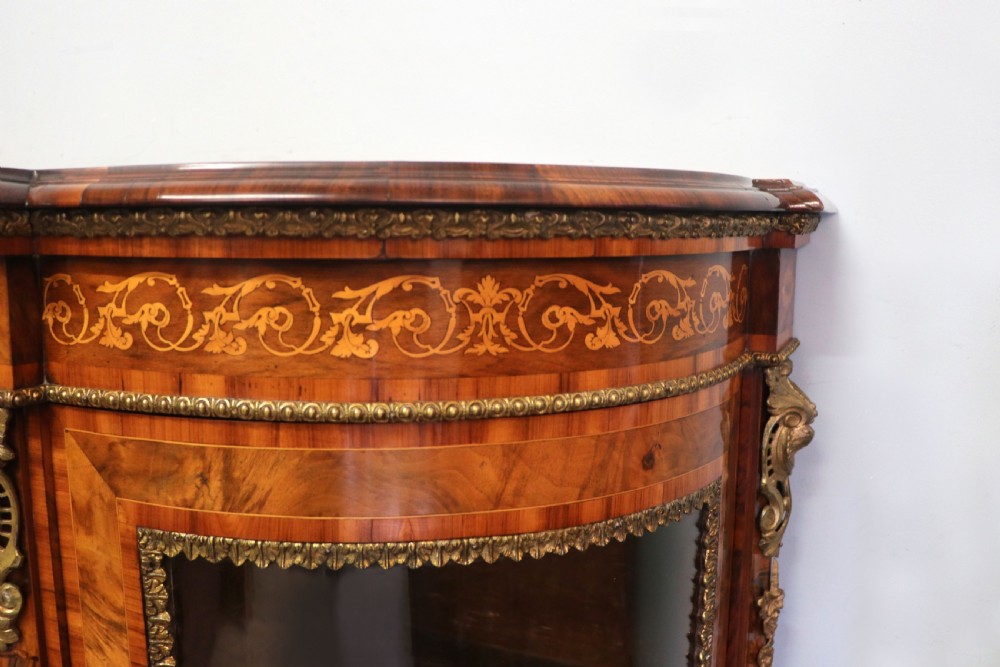 A Victorian walnut credenza featuring floral marquetry inlay, a central glazed door, two curved glass side doors, and gilt metal mounts. View XXIV
