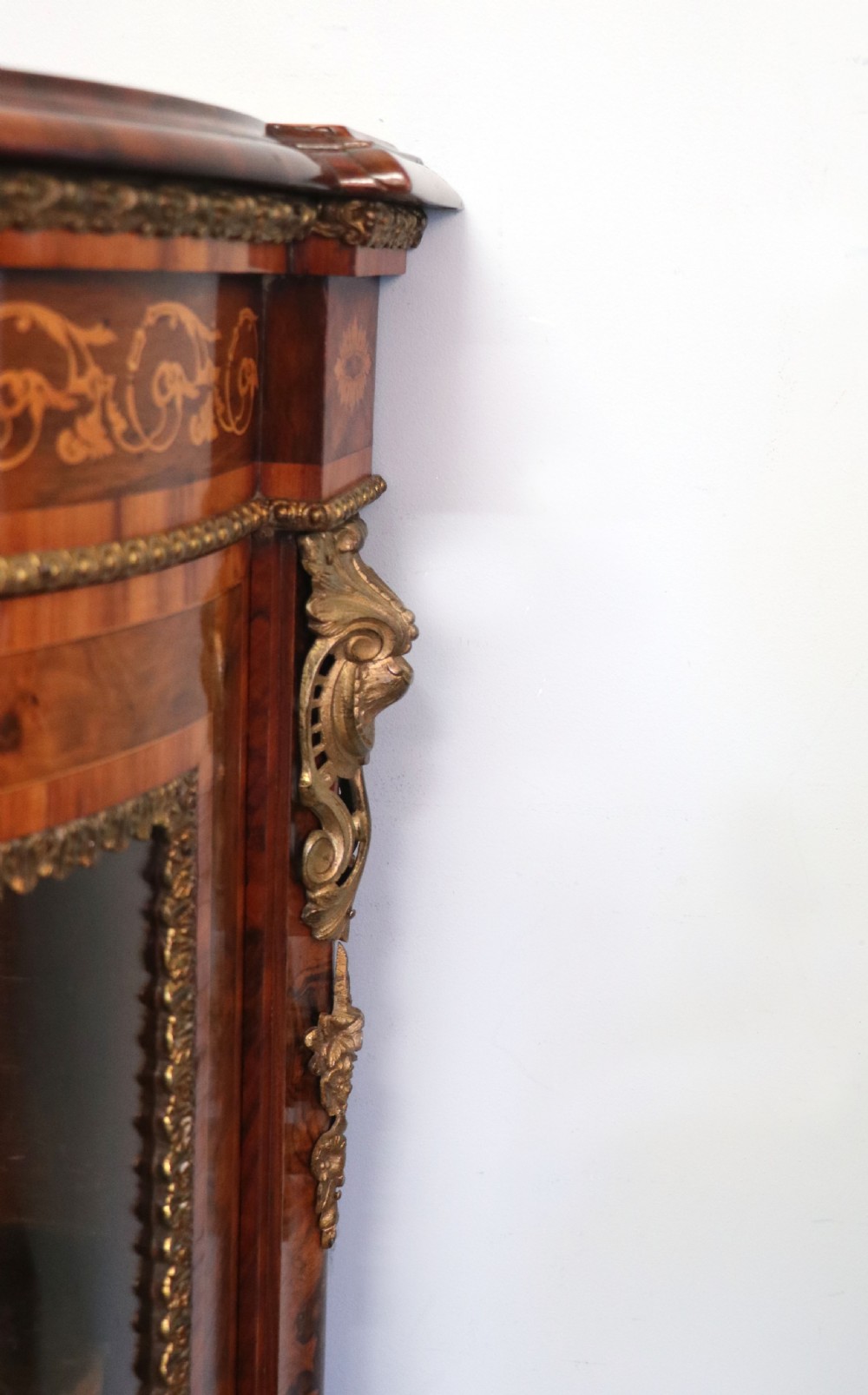 A Victorian walnut credenza featuring floral marquetry inlay, a central glazed door, two curved glass side doors, and gilt metal mounts. View XXV