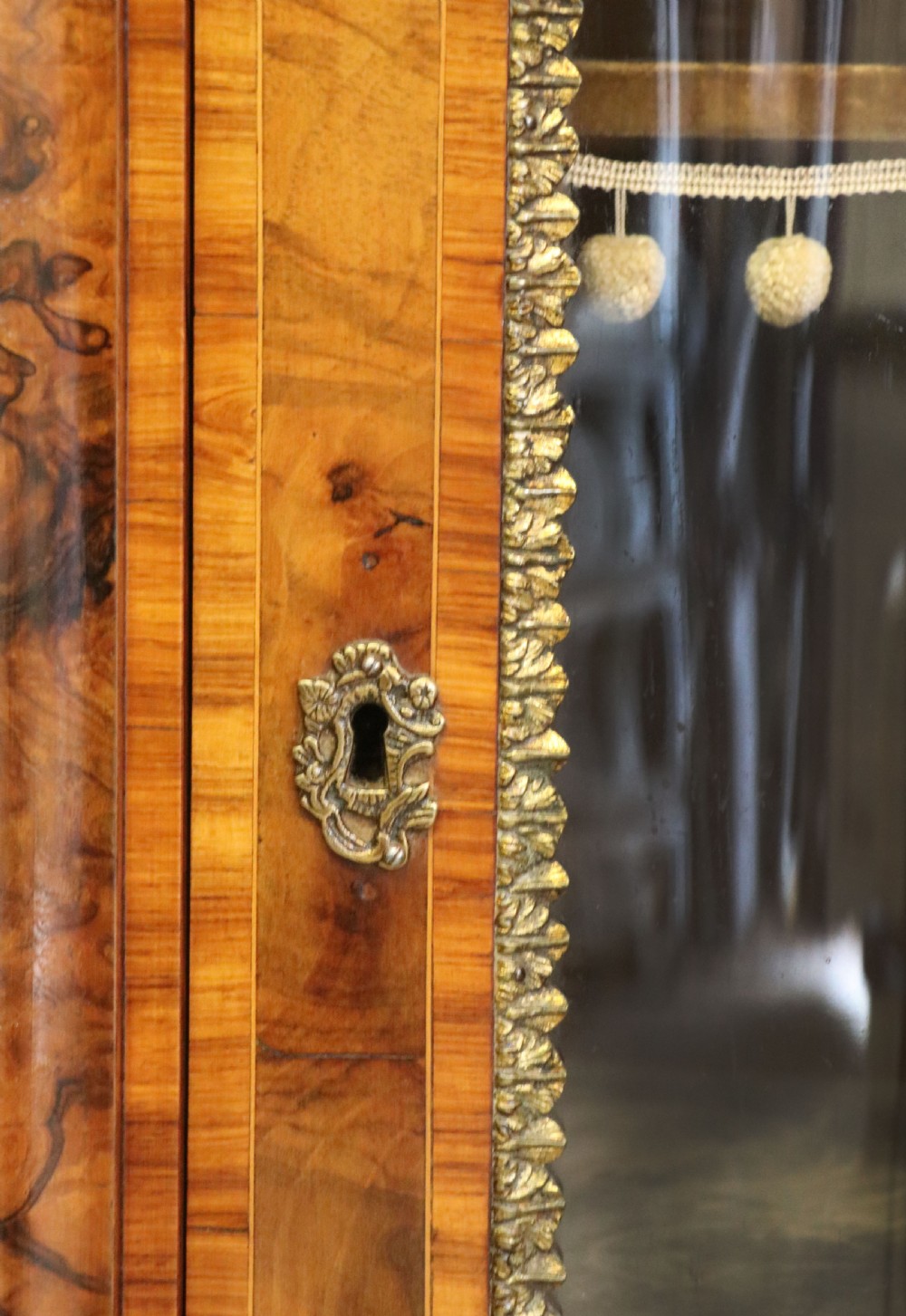 A Victorian walnut credenza featuring floral marquetry inlay, a central glazed door, two curved glass side doors, and gilt metal mounts. View XXX