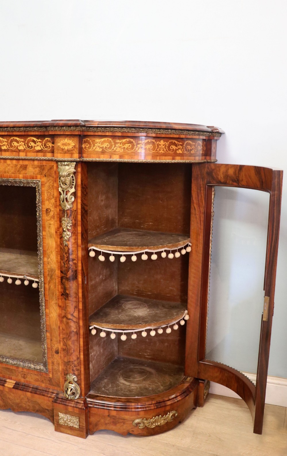 A Victorian walnut credenza featuring floral marquetry inlay, a central glazed door, two curved glass side doors, and gilt metal mounts. View XXXI