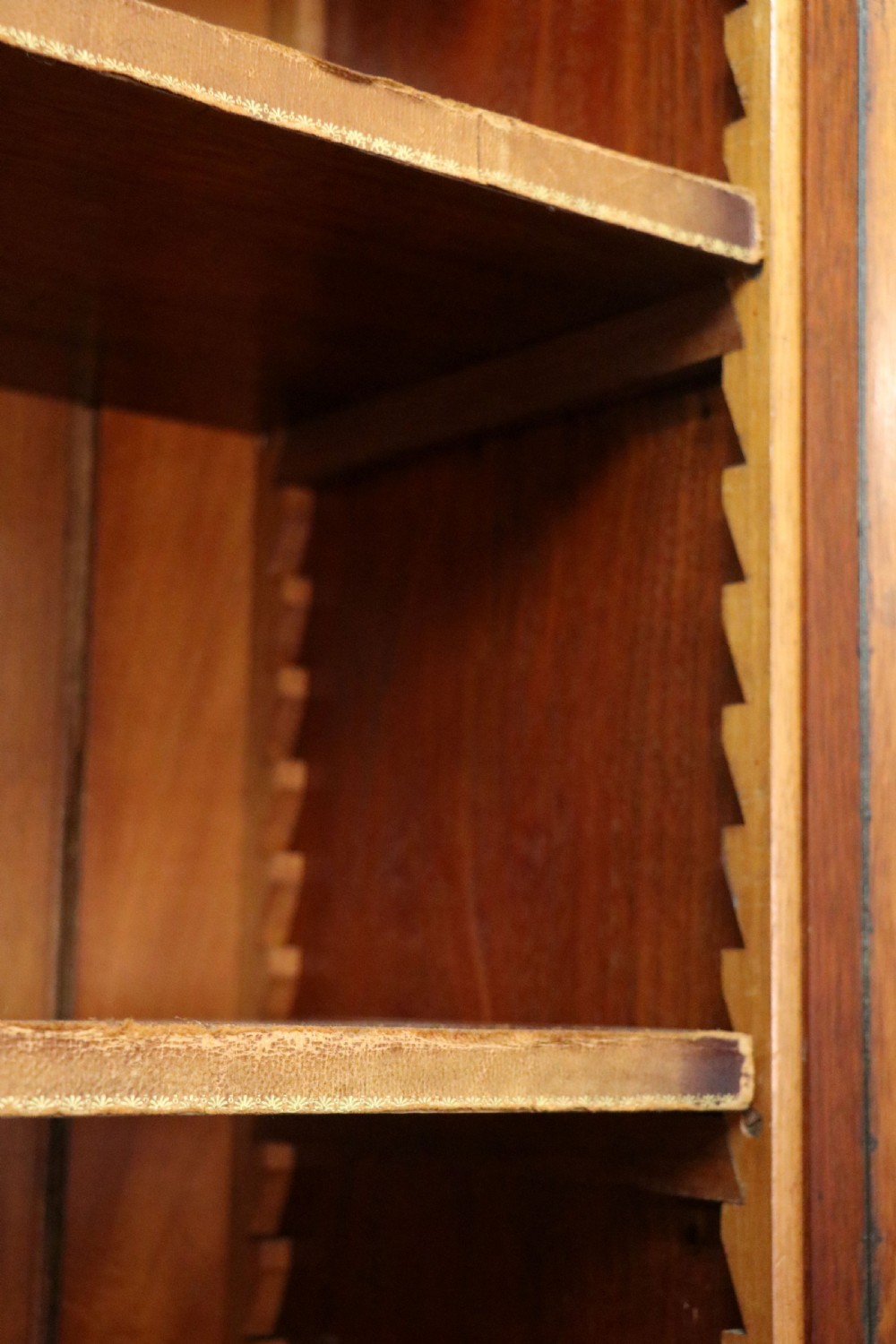 An early Victorian glazed secretaire bookcase cabinet in dark figured wood with carved arch details, a central desk drawer, and lower cupboard doors. View XXV