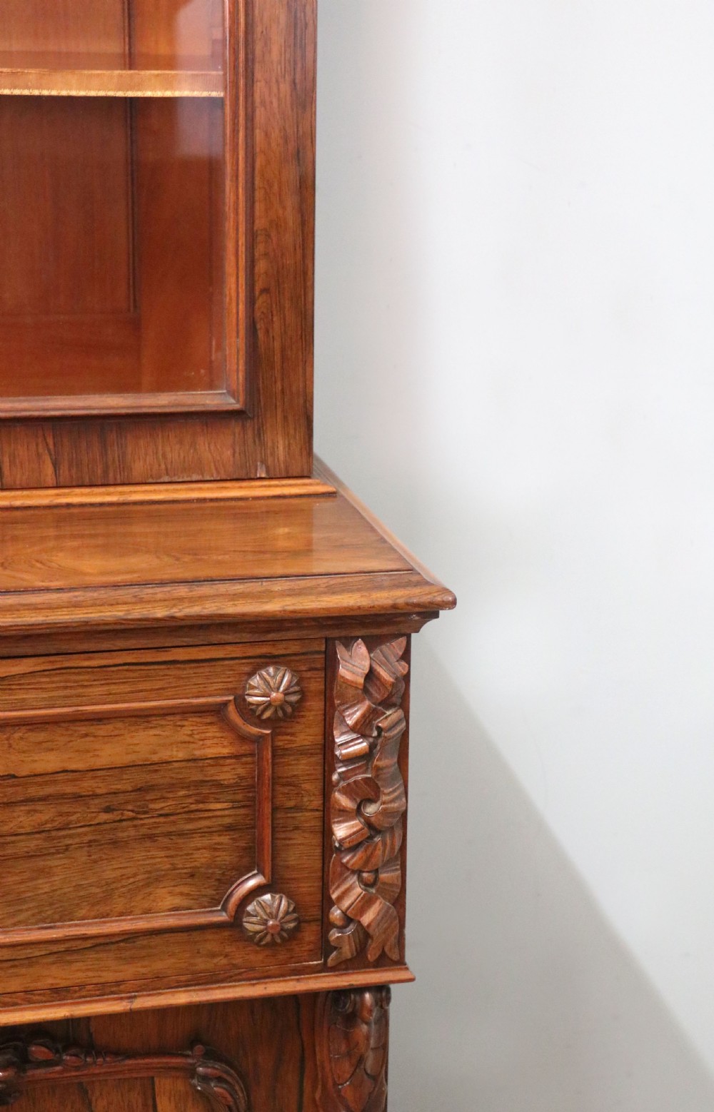 An early Victorian glazed secretaire bookcase cabinet in dark figured wood with carved arch details, a central desk drawer, and lower cupboard doors. View XXVIII