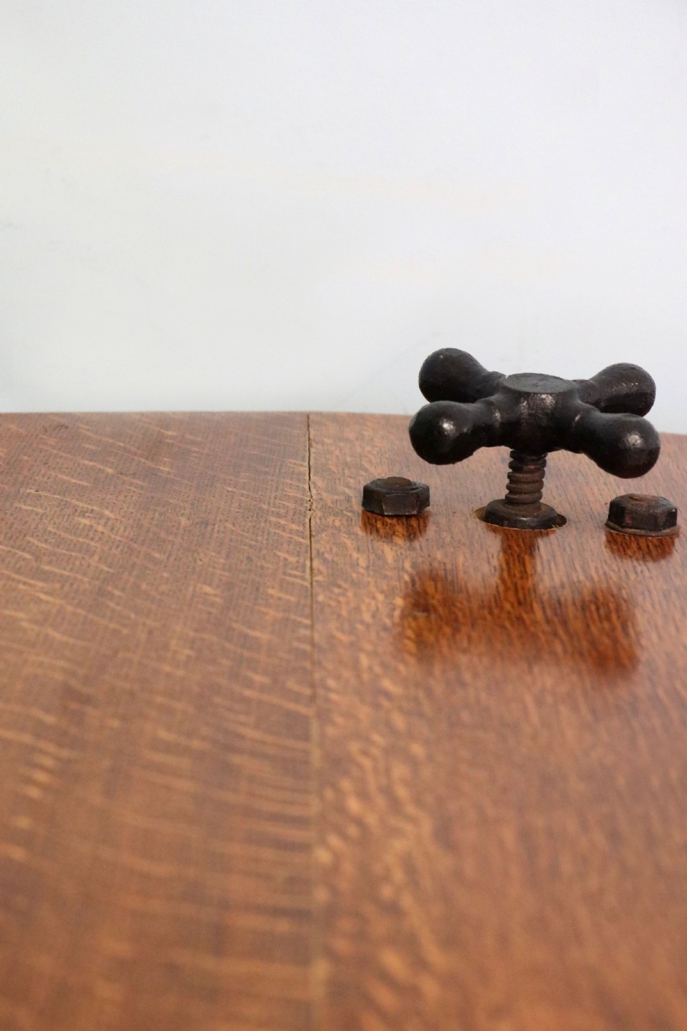 An antique Victorian cast iron mangle with a green and red painted frame, wooden wringer rollers, and a wood tabletop. View XI